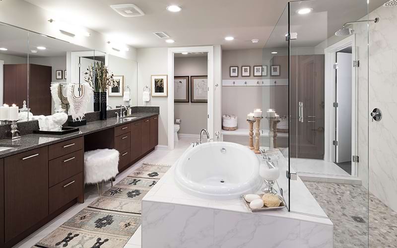 Spacious and well lit bathroom with princess tub and dark wood cabinets